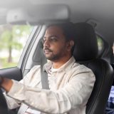 Private chauffeur driving a client through Dubai while the passenger works on a tablet in the back seat