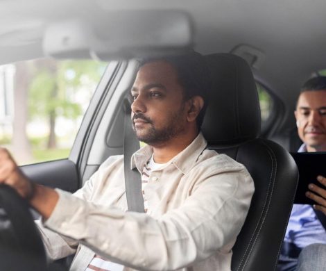 Private chauffeur driving a client through Dubai while the passenger works on a tablet in the back seat